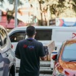 a man walking down a street next to parked cars