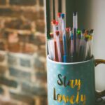 pens in blue ceramic mug in front of window during daytime